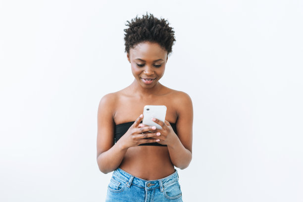 微笑美丽的年轻非洲裔美国妇女在黑色的顶部使用手机孤立在白色的背景图片下载