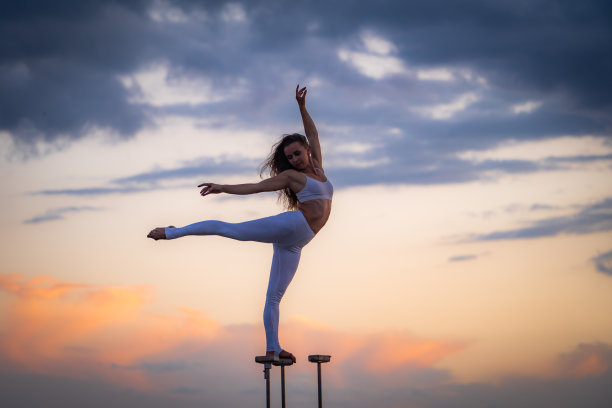 柔韧的健康女孩在日落时分做瑜伽劈叉的剪影图片下载