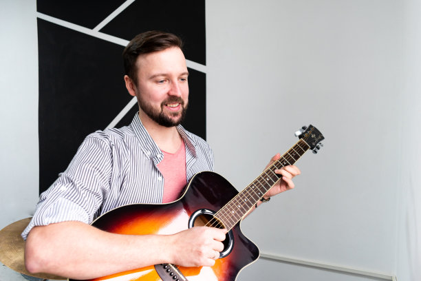 男音乐家正在木吉他上弹奏音乐，用手指捕捉和弦。图片下载