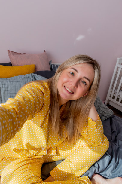 年轻女子醒来，拍了一张自拍。早上在床上。图片下载