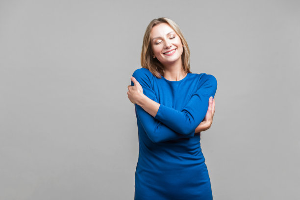 我爱我自己。满足自私的女人拥抱自己的画像。室内摄影棚拍摄孤立的灰色背景图片下载