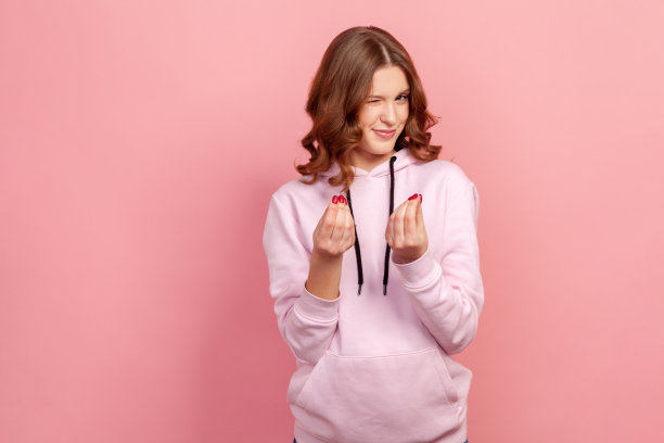 肖像狡猾的十几岁的女孩在帽衫微笑狡猾，显示给我钱的手势，要求支付，零用钱图片下载