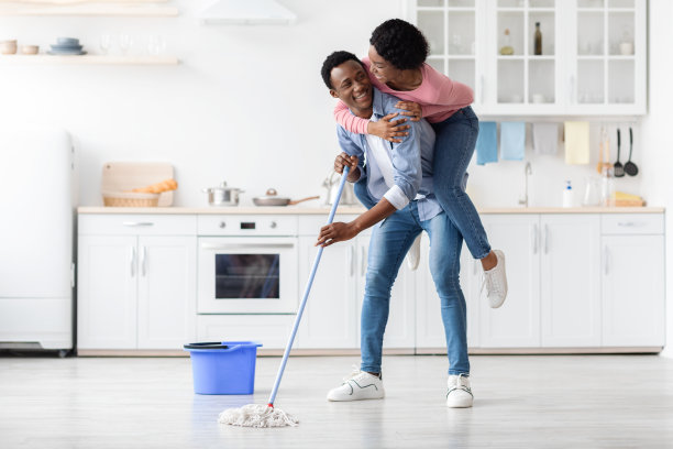 一对可爱的黑人夫妇在拖厨房的时候玩得很开心图片下载