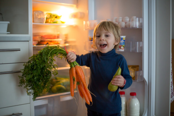 可爱的蹒跚学步的金发小孩，打开冰箱门，拿水果、蔬菜和健康食品图片下载