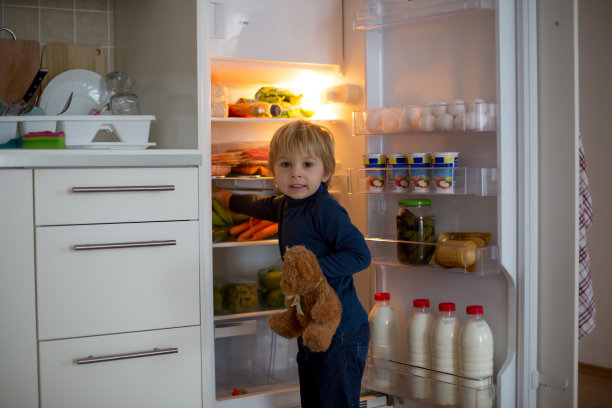可爱的蹒跚学步的金发小孩，打开冰箱门，拿水果、蔬菜和健康食品图片下载