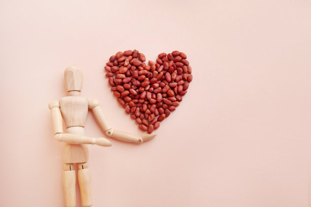 生花生被做成心形放在一个木制玩偶的手上。前视图。图片下载