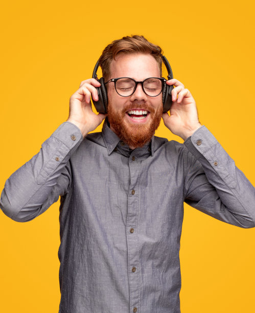 一个戴着耳机听音乐的快乐的大胡子男人图片下载