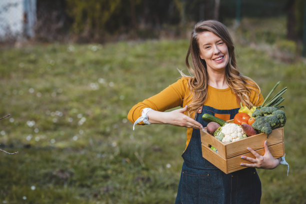 农妇拿着装满新鲜生蔬菜的木箱子。图片下载