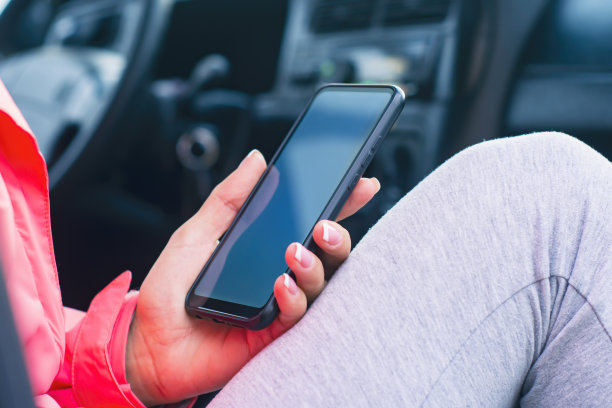 车里的女孩拿着一个白色屏幕的智能手机模型。模型技术。图片下载