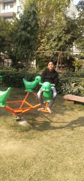 英俊的小男孩在操场上玩。图片下载