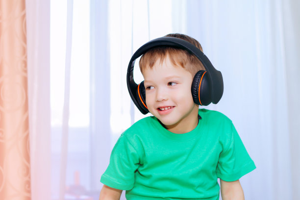 一个金发白种男孩穿着一件绿色t恤戴着黑色大耳机图片下载