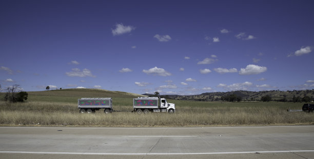 位于悉尼和墨尔本之间的澳大利亚小镇上的一条高速公路，美丽的蓝天和郁郁葱葱的树木作为背景图片下载