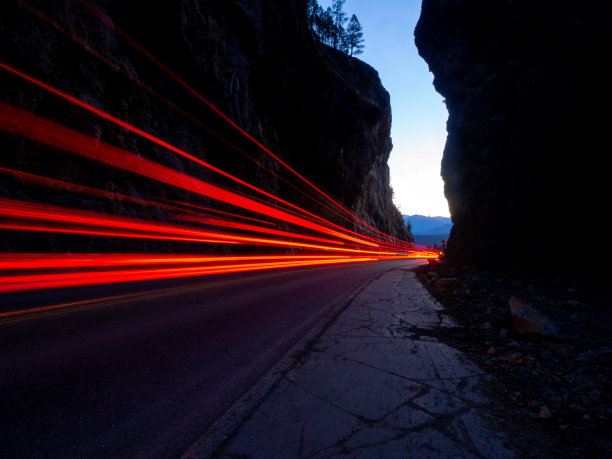 在晴朗的蓝天下，红色的汽车在峡谷中行驶图片下载