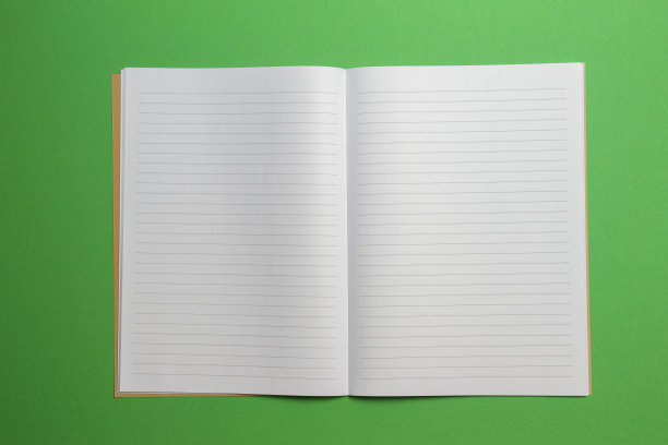 空打开条纹笔记本在绿色的背景。俯视图图片下载