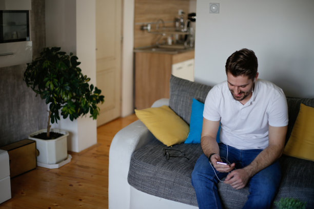 年轻人带着耳机在家欣赏音乐的照片图片下载