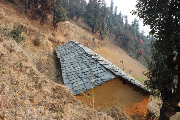 这是印度喜玛拉雅地区位于山坡上的一个传统的泥和石头房子的图片。图片下载