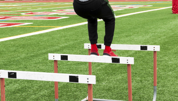 运动员在草坪上跳过跑道跨栏时穿着黑色弹力衣的双腿图片下载