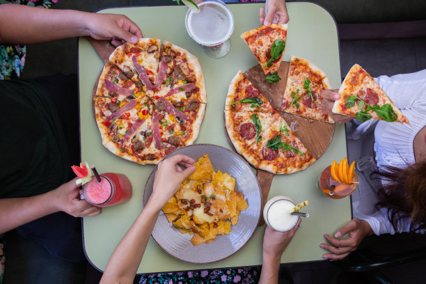 俯视图的手从餐厅或咖啡馆的桌子上拿披萨和零食。庆祝，聚会或事件的概念。图片下载