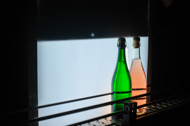 近距离照片上的两瓶起泡酒在装瓶和密封输送带在酒厂图片下载