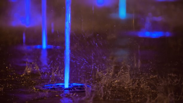 喷溅着五彩缤纷的喷泉。水被照亮，以不同的颜色落在一个喷泉，改变其水的颜色在夜晚。图片下载