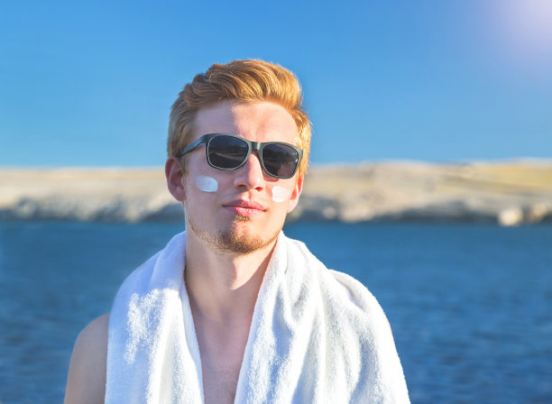 有魅力的男人用防晒霜在脸上护理他的身体。图片下载