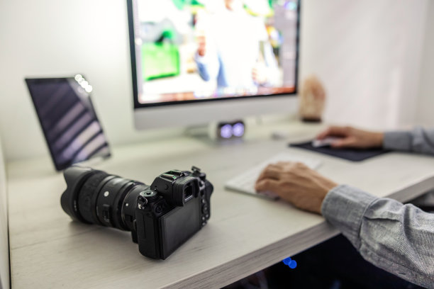 照片变焦在一个专业的黑色相机与物镜。一个男人的手在桌面上编辑键盘和原材料。摄影爱好者，工作和爱好图片下载
