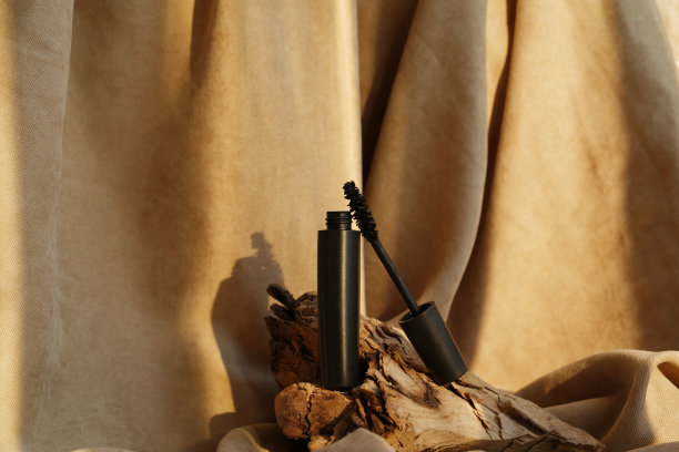 睫毛膏瓶和刷子停留在木头上的棕色自然背景。时尚的眼部化妆品。图片下载