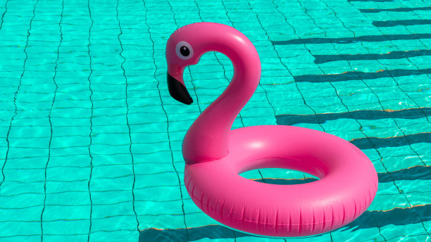 你好,夏天。粉红色的充气火烈鸟在游泳池的水为夏天的海滩背景。时尚的夏天的概念。图片下载