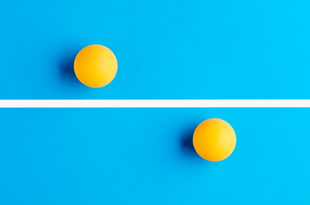 两个橙色的乒乓球互相对立，被蓝色背景上的一条线分开。图片下载