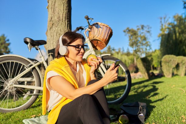 快乐放松成熟的女人戴着耳机和智能手机图片下载