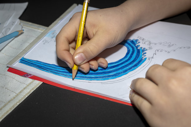 手拿钢笔的一个孩子正在画一幅画。图片下载