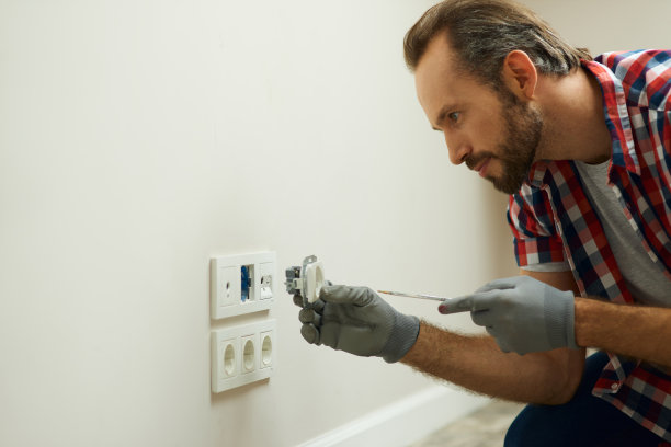 照片中的电工戴着防护手套，使用螺丝刀安装新的插头插座图片下载