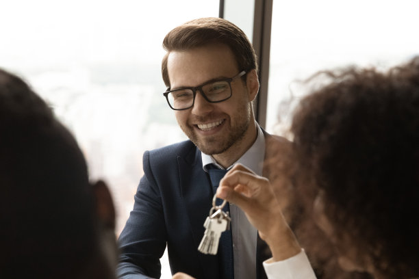 近距离微笑的白人房地产经纪人给客户钥匙图片下载