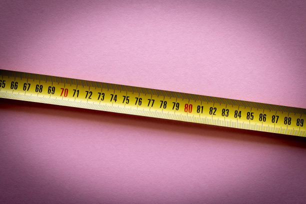 粉红色背景上的黄色卷尺。特写镜头。图片下载