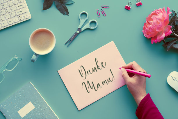 母亲节贺卡。短信Danke Mama在德语中的意思是谢谢你妈妈。淡红的牡丹花在褪了色的薄荷绿桌上。咖啡，键盘，花，键盘，家庭办公室。时髦的俯视图，平躺图片下载
