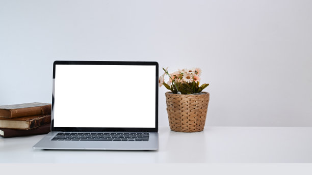 打开空白屏幕的笔记本电脑，白色书桌上的书和花盆。图片下载