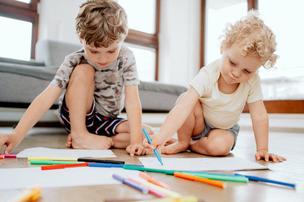 快乐的孩子。小男孩和小女孩在复古的棕色地板上的创意照片。孩子们躺在标记和绘画之间图片下载