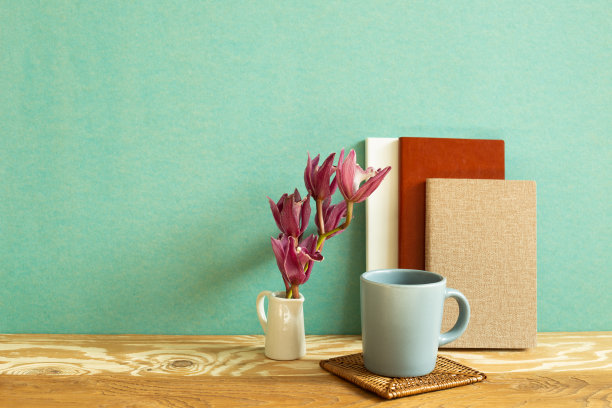 笔记本，马克杯，木桌上放花。绿色背景。工作和学习场所图片下载