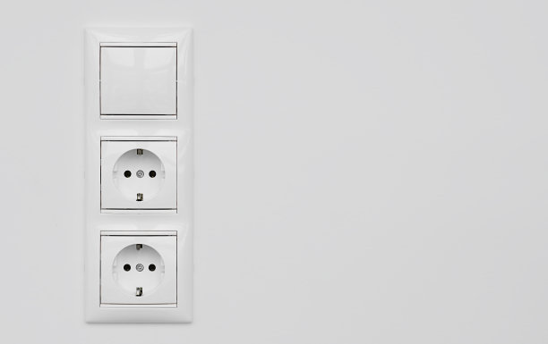 两个白色塑料插座和一个开关隔离在白色的灰泥墙上。电子欧洲插座关闭拷贝空间图片下载