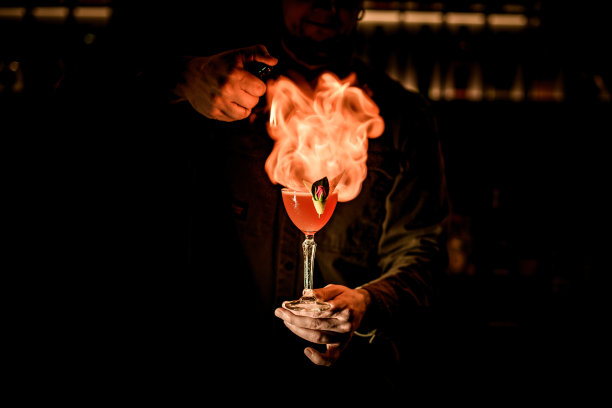 酒保手持酒杯，在黑暗的酒吧里熟练地点燃了火焰图片下载