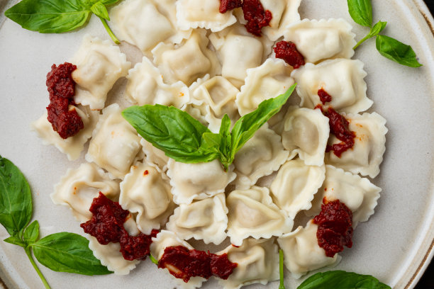 开胃的意大利饺子配番茄酱、奶酪和罗勒，罗勒帕尔马干酪和番茄放在白色盘子上，在旧的深色木桌的背景上，俯视图平铺图片下载