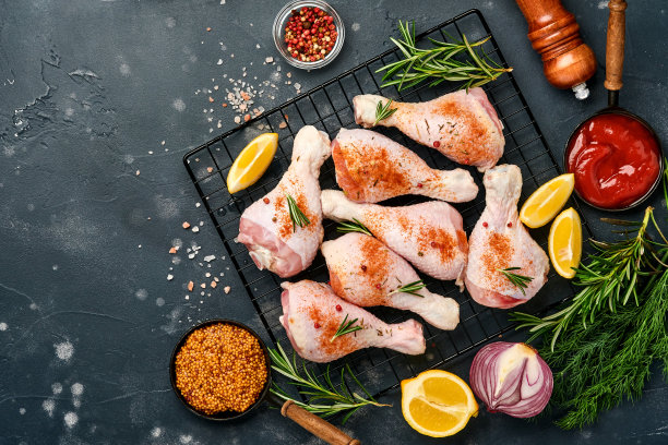 生鸡腿和烹饪材料在黑色的石头背景。食物背景，生肉与香料在黑色的桌子。前视图。图片下载