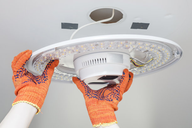 电工在天花板上安装一盏枝形吊灯。电工的手安装和连接灯到天花板。图片下载