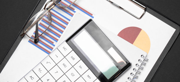 簿记员工作场所概念。顶部以上俯瞰照片的办公室配件计算器，钢笔，剪贴板，笔记本孤立的黑色背景图片下载