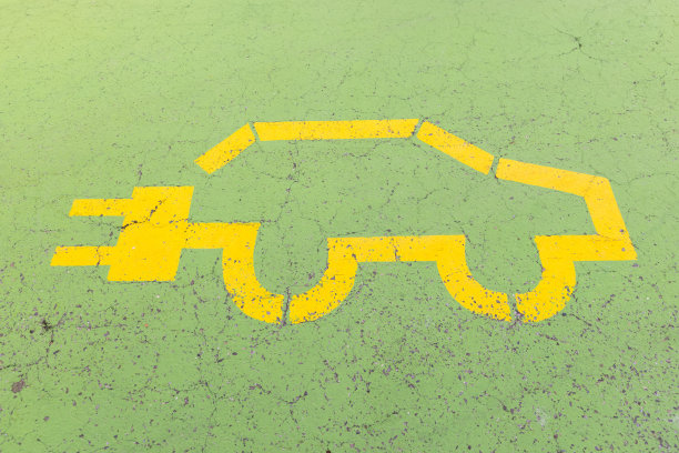 黄色的电动汽车标志画在绿色的混凝土地板上，没有人图片下载