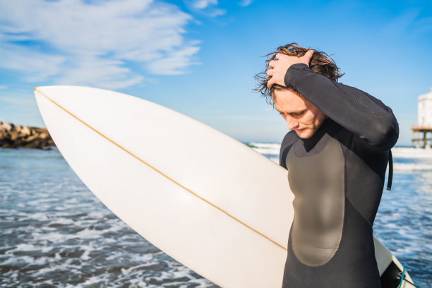 冲浪者拿着冲浪板站在海里。图片下载