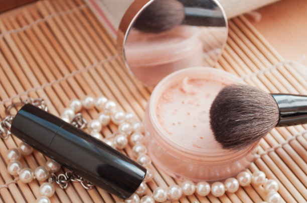 女人的化妆品。松散的矿物粉与粉刷的背景粉珠子和礼品盒。图片下载