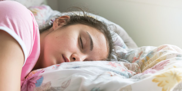 穿着t恤的女学生睡在大床上抱着枕头图片下载