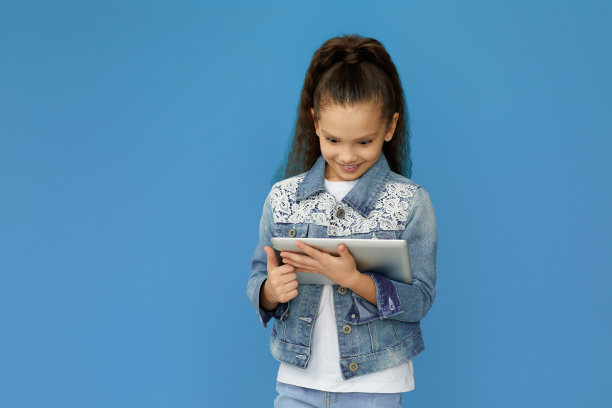 穿着牛仔布的小女孩用数码平板电脑图片下载