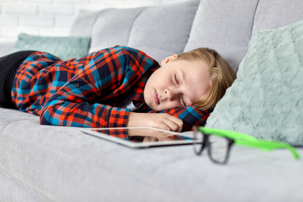 疲惫的孩子拿着药片在沙发上睡着了图片下载